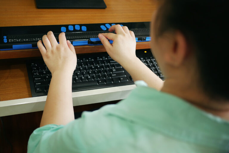 An individual with a vision disability uses keyboard with braille to access website.