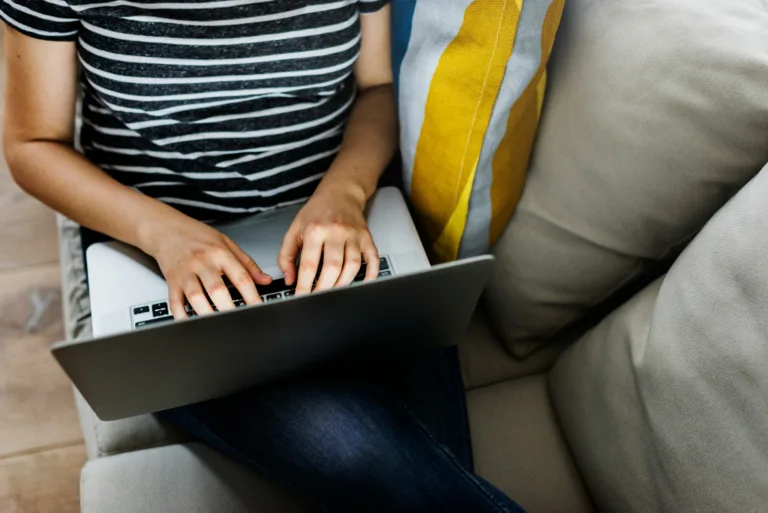 woman with laptop in lap searching the web