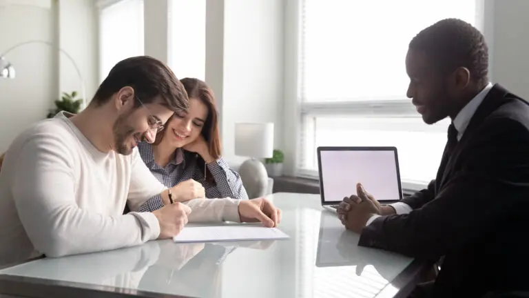 Young Millennial couple signing real estate contract with lawyer.