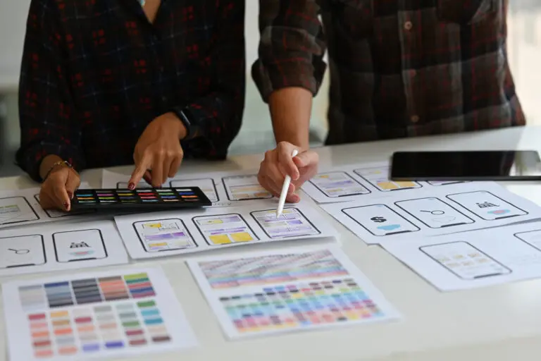 hands of designers looking at wireframes on table