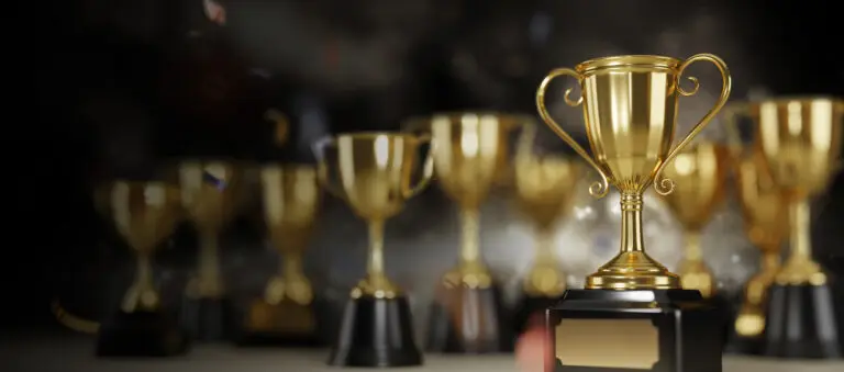 A number of gold trophies against a black background