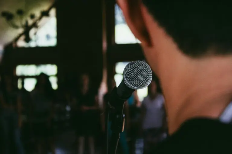 back of man's head, as he stands at microphone and looks into crowd of people